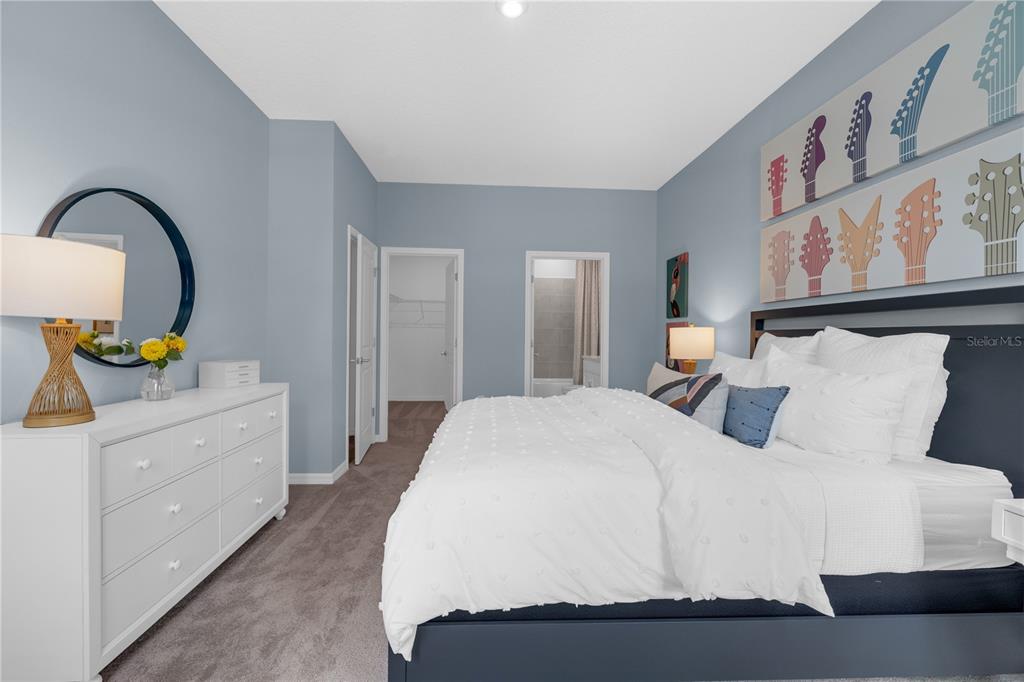 A bedroom features a white dresser, a bed with blue frame, and guitar-themed wall art — 6755 WINTERBERRY DRIVE, LAKE HAMILTON, FL