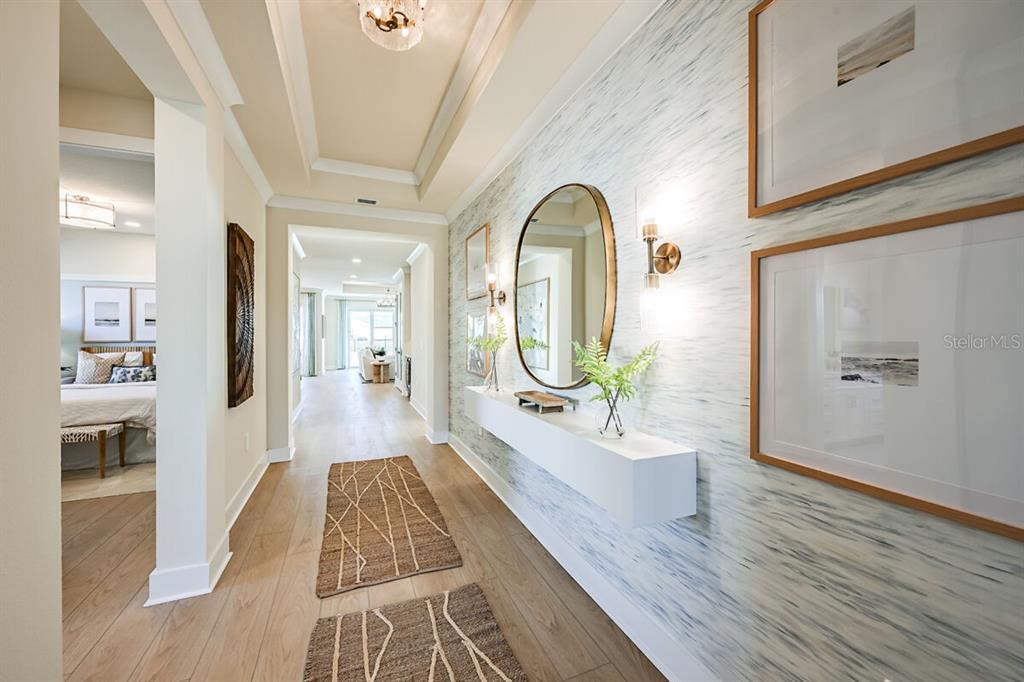 A hallway features a floating shelf, a round mirror, textured wallpaper, and two framed prints — 13685 LOREDO WAY, PUNTA GORDA, FL