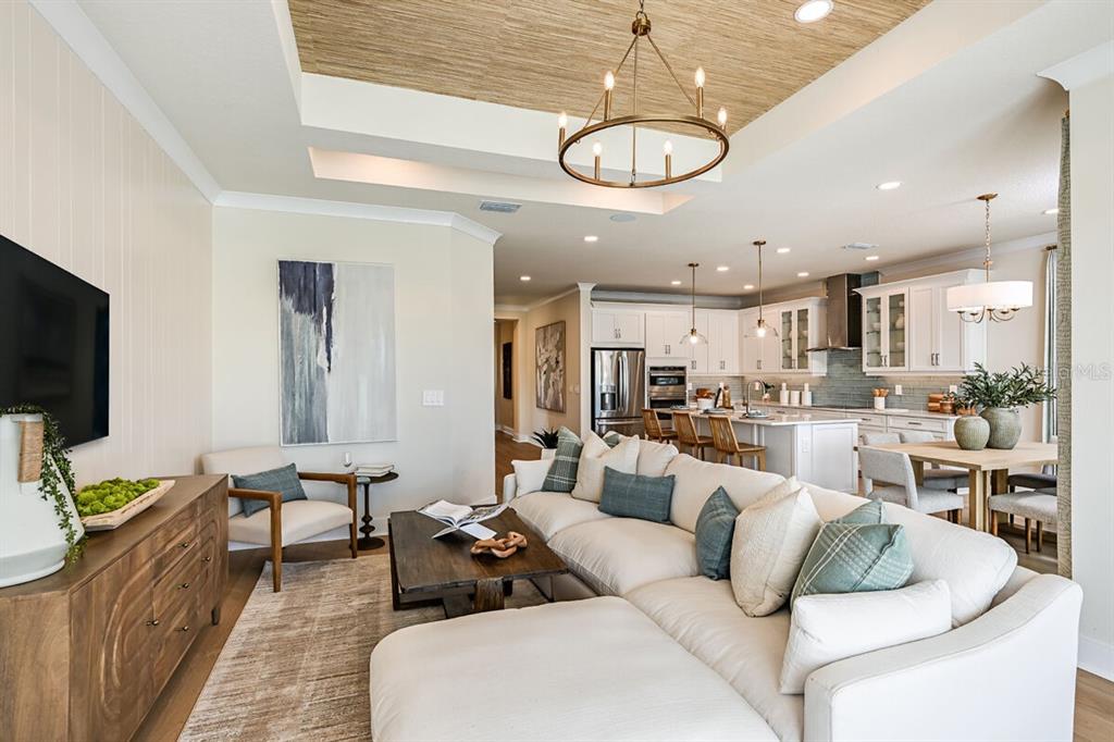 A bright, open-concept living room and kitchen featuring a tray ceiling and neutral decor — 13685 LOREDO WAY, PUNTA GORDA, FL
