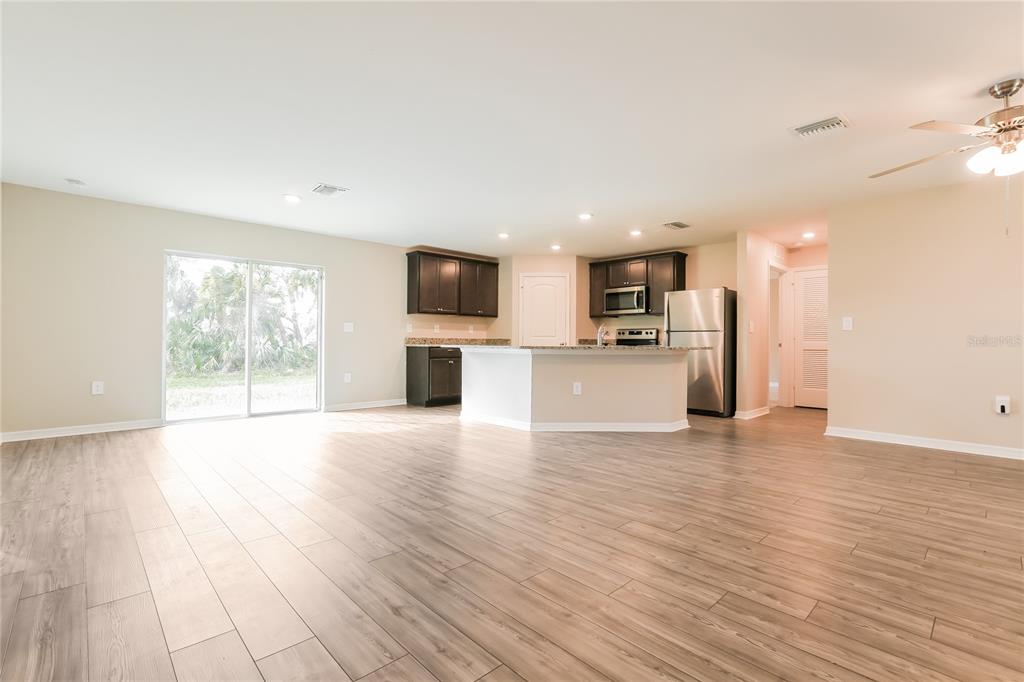 An open-concept kitchen with dark cabinets and stainless steel appliances overlooks a spacious living area — 2443 ZODIAC STREET, NORTH PORT, FL