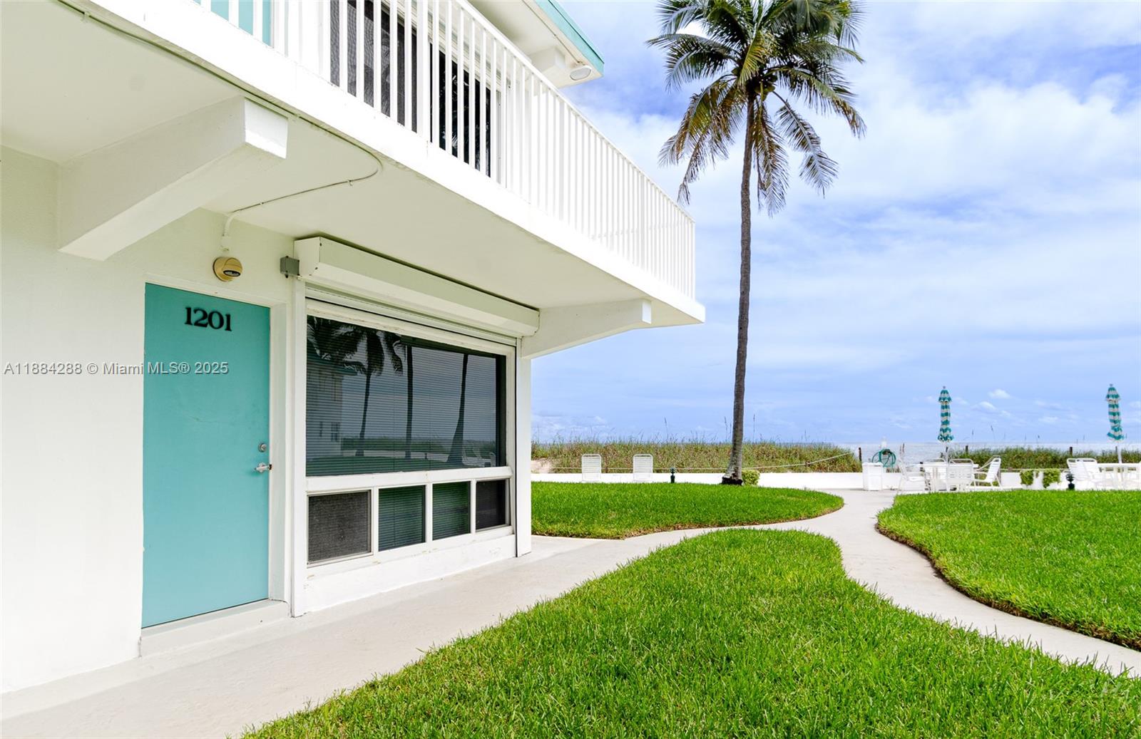 A teal door labeled 1201 sits beside a large window under a white balcony — 1470 S Ocean Blvd # 1201, Pompano Beach FL 33062, POMPANO BEACH, FL