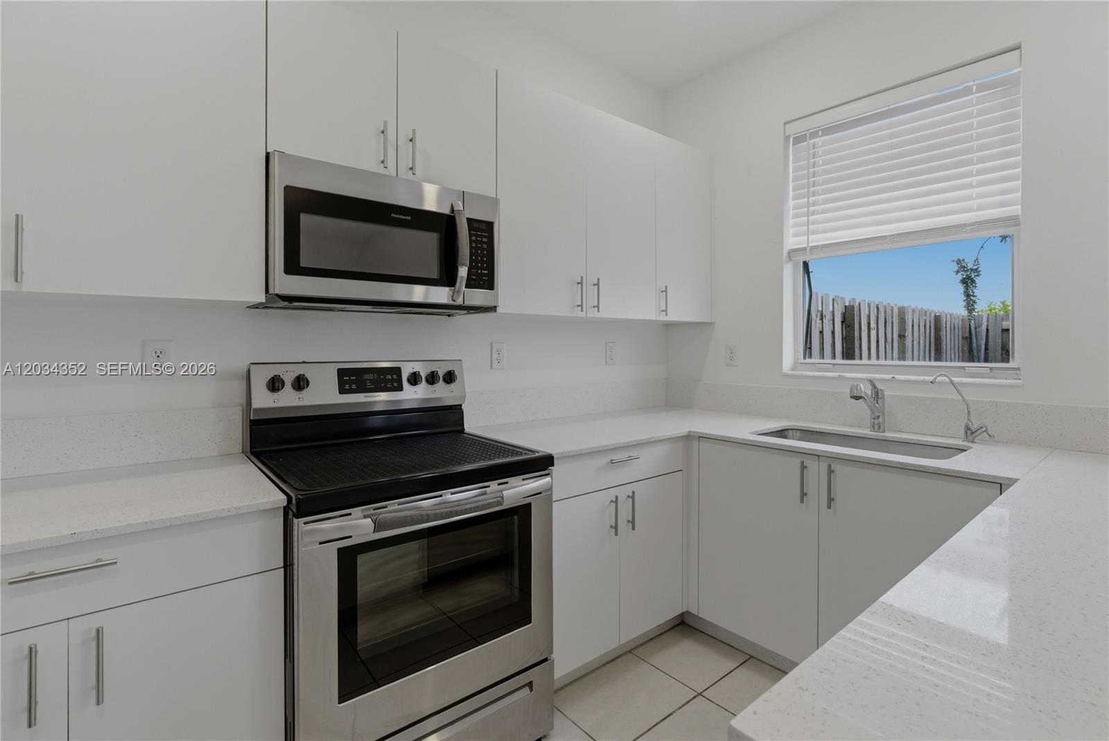 A kitchen features white cabinets, stainless steel appliances, and light countertops under a window — 16314 SW 291 ST # 16314, Miami FL 33033, MIAMI, FL