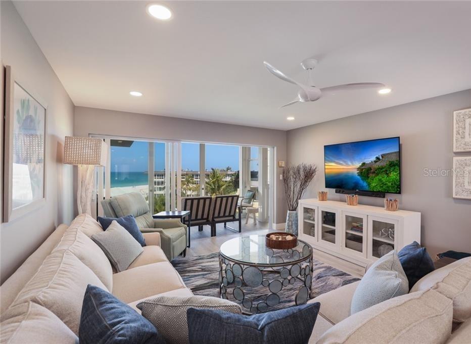 A living room features a sectional sofa, glass coffee table, media console, and balcony view — 2110 BENJAMIN FRANKLIN DRIVE UNIT 503SEA, SARASOTA, FL