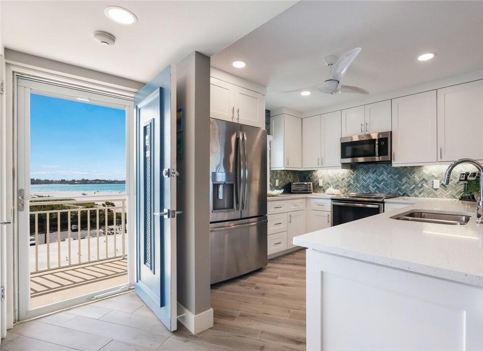 A kitchen with white cabinets, stainless steel appliances, and a door opening to a balcony — 2110 BENJAMIN FRANKLIN DRIVE UNIT 503SEA, SARASOTA, FL