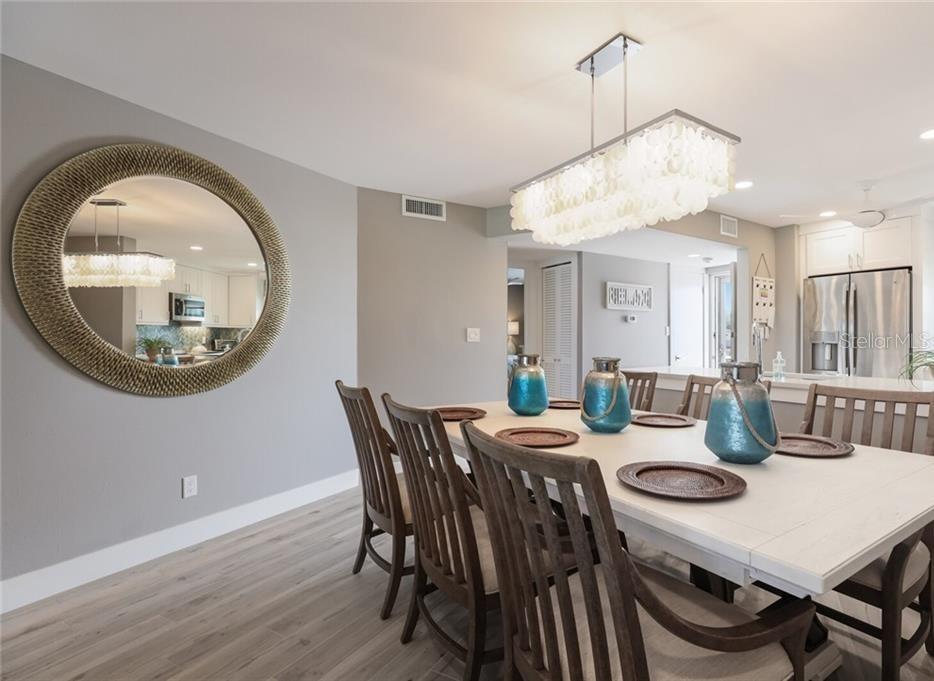 A dining room features a white table, wooden chairs, a large round mirror, and chandelier — 2110 BENJAMIN FRANKLIN DRIVE UNIT 503SEA, SARASOTA, FL
