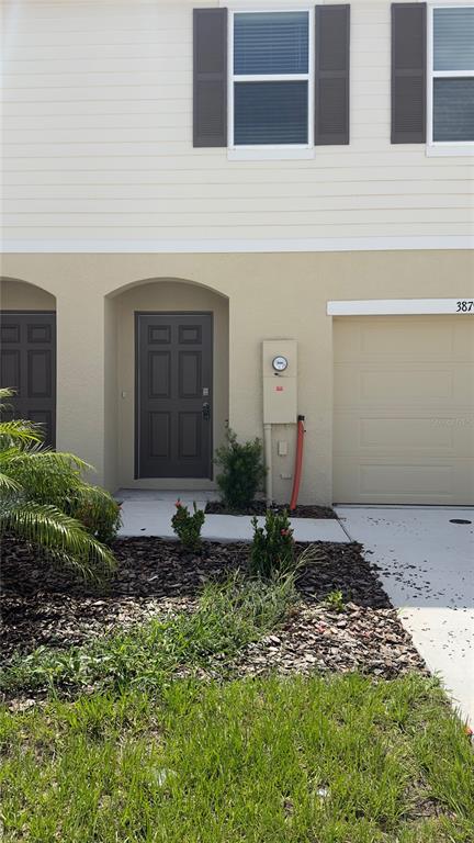 The exterior of a two-story townhouse features a dark front door, garage, and landscaping — 3879 ACADEMIA AVENUE, LAKELAND, FL