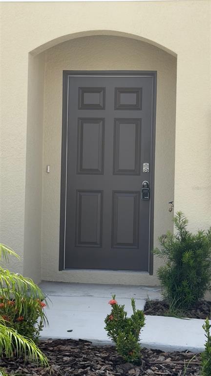 A dark gray six-panel front door is set within an arched entryway of a home — 3879 ACADEMIA AVENUE, LAKELAND, FL
