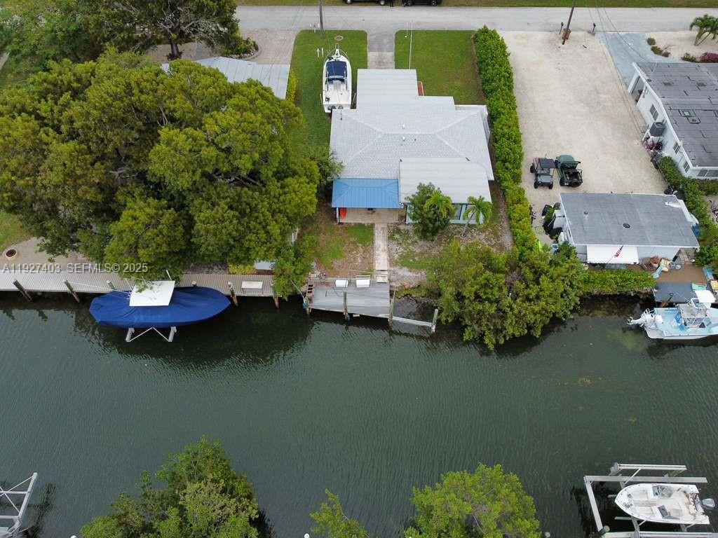 An aerial view shows a waterfront house with a boat dock and surrounding trees — 1403 Grouper Dr, Marathon FL 33050, MARATHON, FL