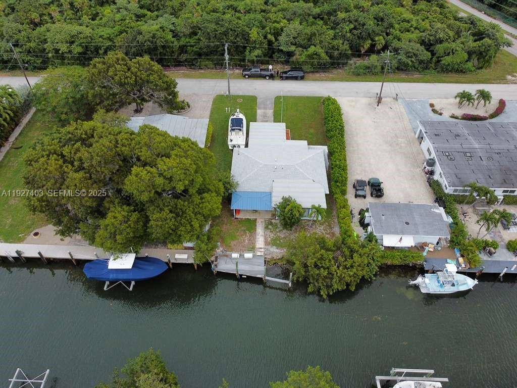 An aerial view shows a waterfront house with a boat dock and a large tree — 1403 Grouper Dr, Marathon FL 33050, MARATHON, FL