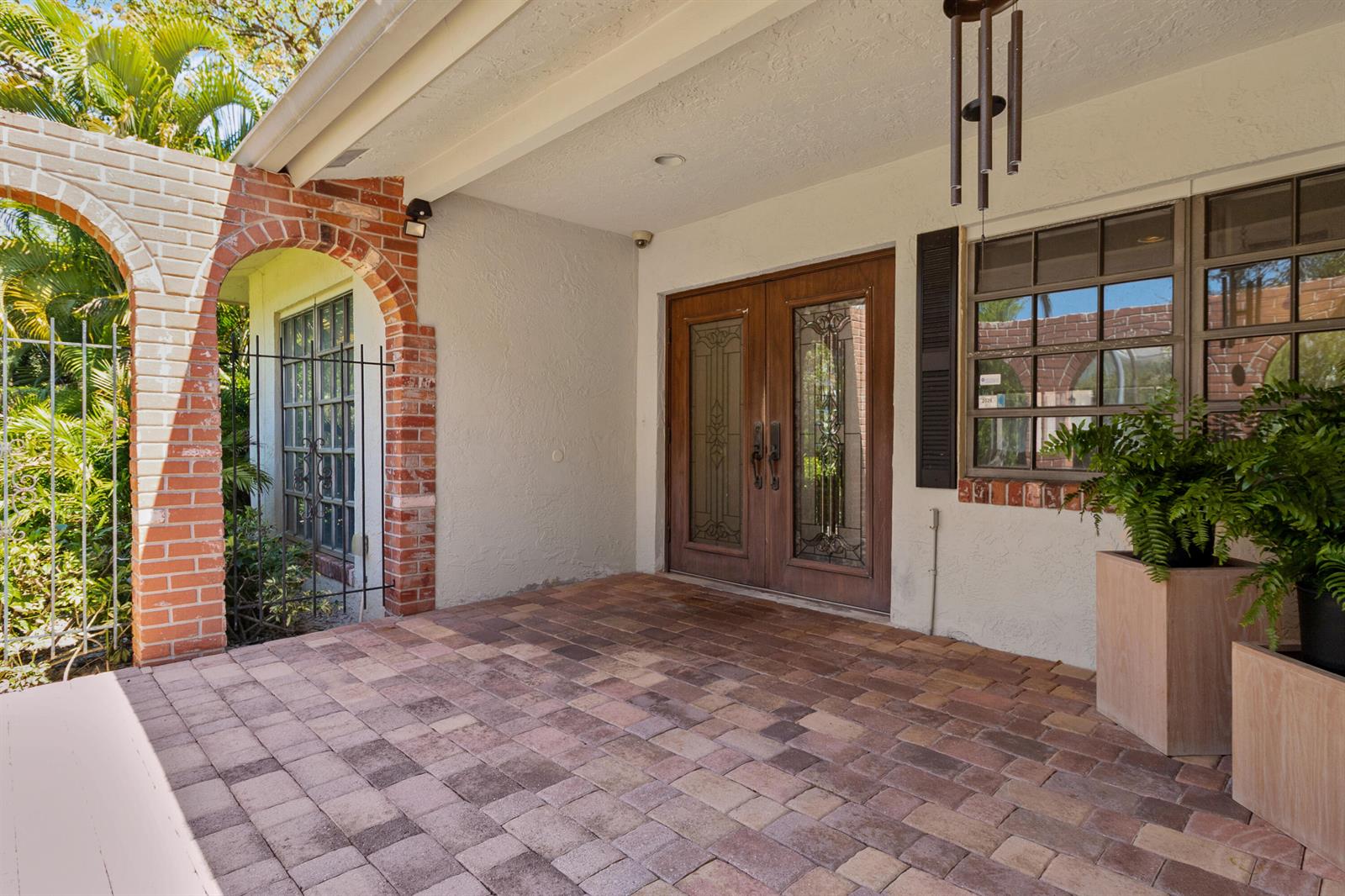 A covered brick-paved entryway features double wooden doors with glass inserts and brick archways — 1350 W Terra Mar Drive, Pompano Beach FL 33062, POMPANO BEACH, FL