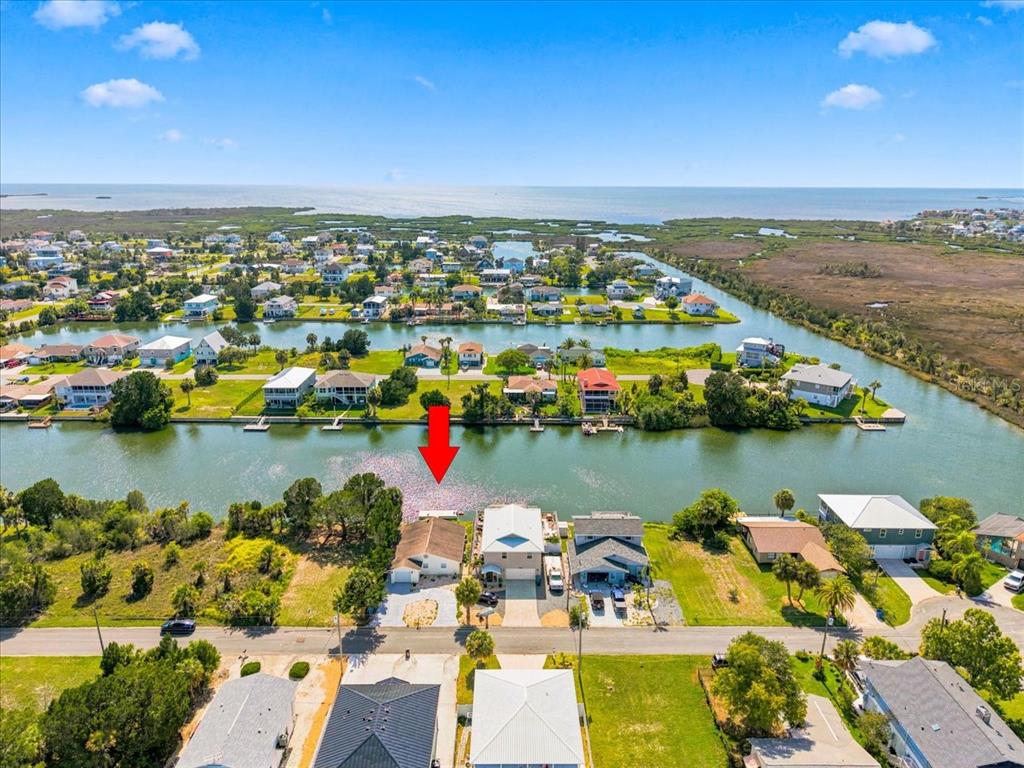 An aerial view shows a waterfront house with a red arrow pointing to its dock — 3385 HOLLY SPRINGS DRIVE, HERNANDO BEACH, FL