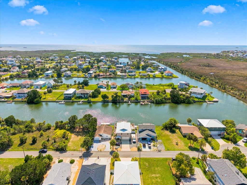 An aerial view shows waterfront houses along canals leading toward a large body of water — 3385 HOLLY SPRINGS DRIVE, HERNANDO BEACH, FL