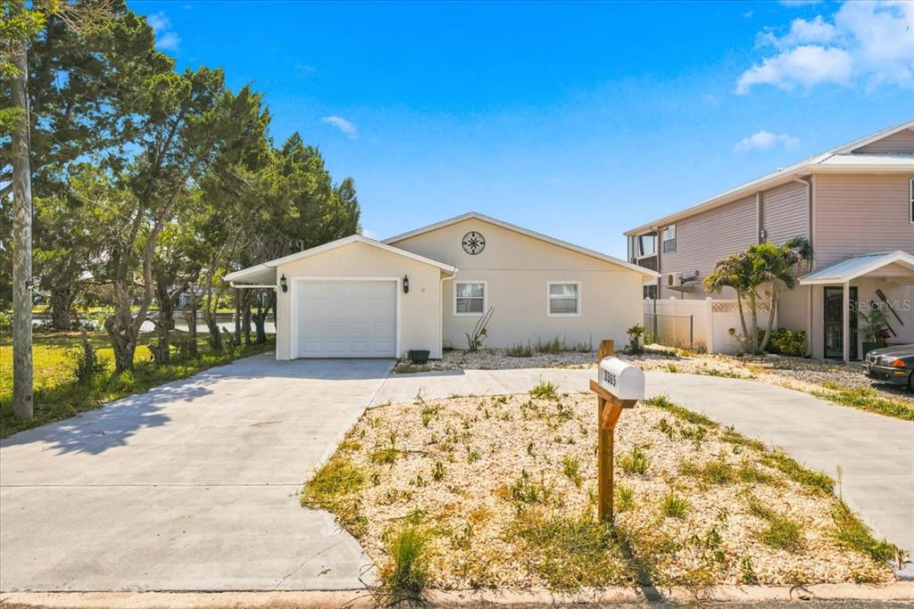 A single-story house with a white garage and a gravel front yard — 3385 HOLLY SPRINGS DRIVE, HERNANDO BEACH, FL