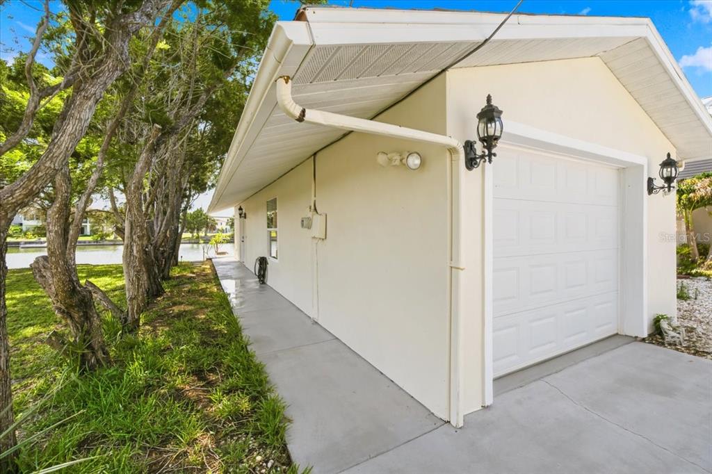 The exterior of a house features a white garage, a concrete walkway, and nearby trees — 3385 HOLLY SPRINGS DRIVE, HERNANDO BEACH, FL