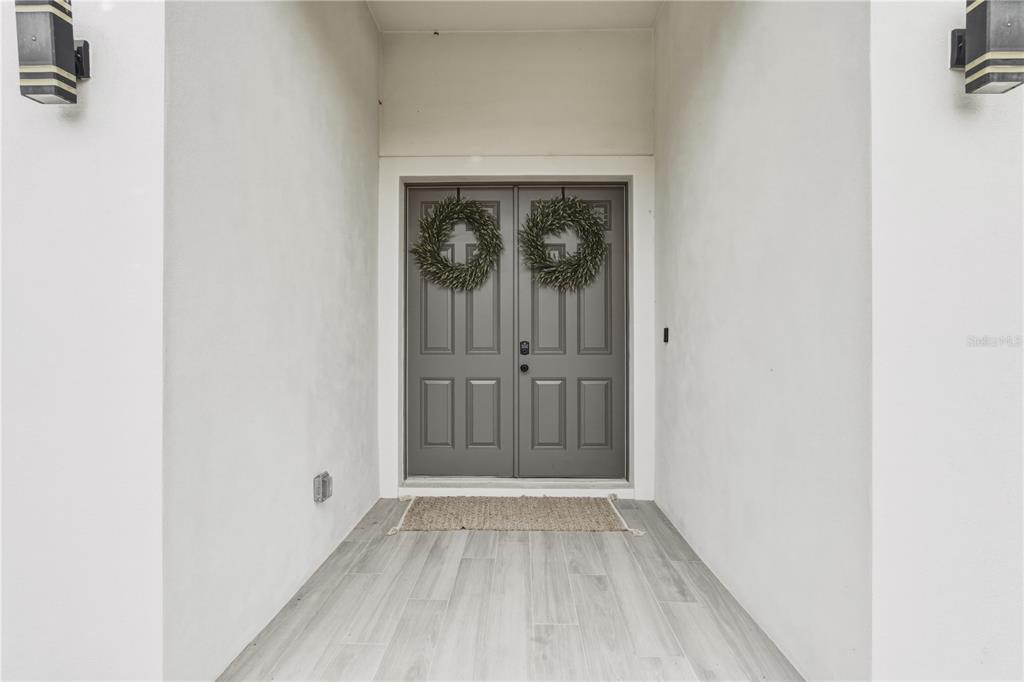 A gray double front door with wreaths sits at the end of a covered entryway — 4143 UNION LANE, NORTH PORT, FL