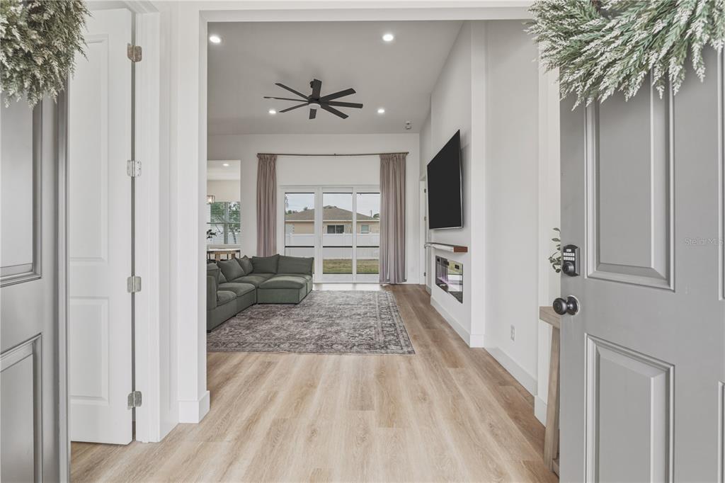 A view from an open doorway into a living room with light wood-look flooring — 4143 UNION LANE, NORTH PORT, FL