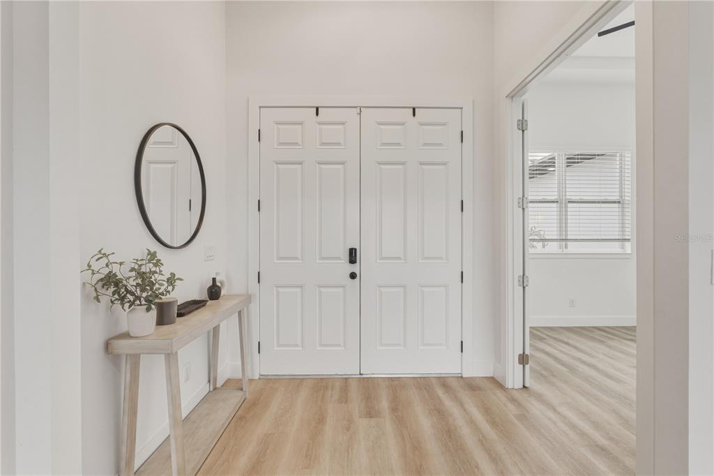 A bright entryway features white double doors, light wood-look flooring, and a console table — 4143 UNION LANE, NORTH PORT, FL
