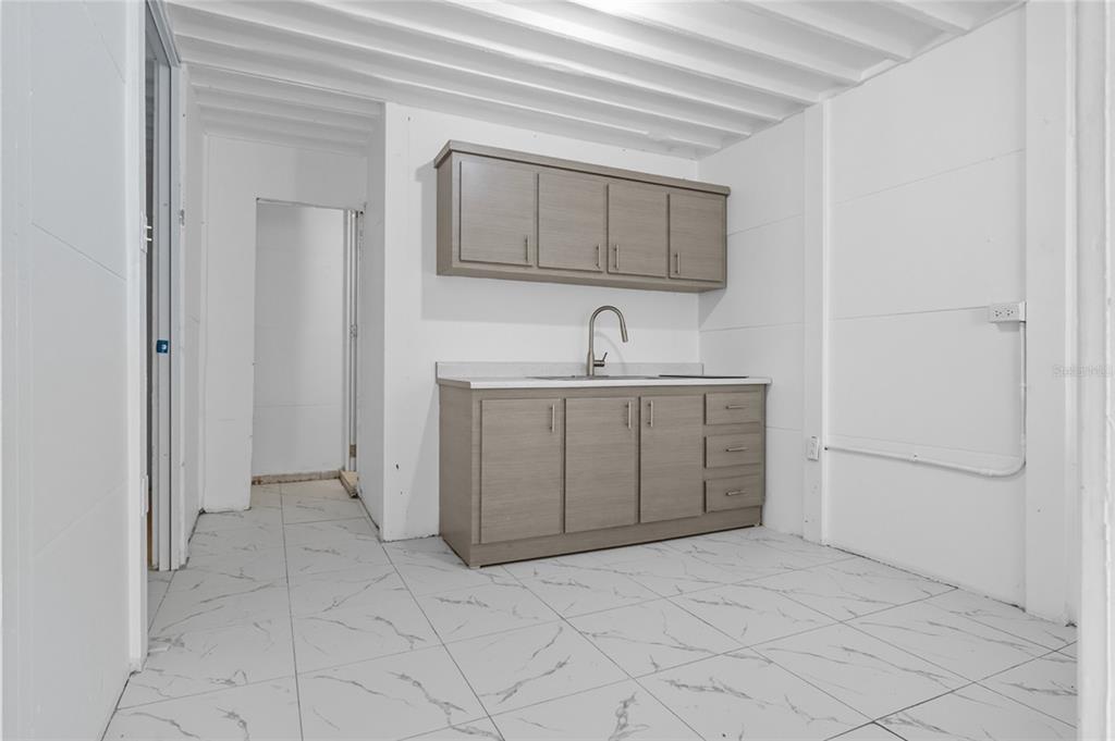 A small kitchen area features gray cabinets, a sink, and white marble-patterned tile flooring — 36 RAMON B LOPEZ STREET, SAN JUAN, PR
