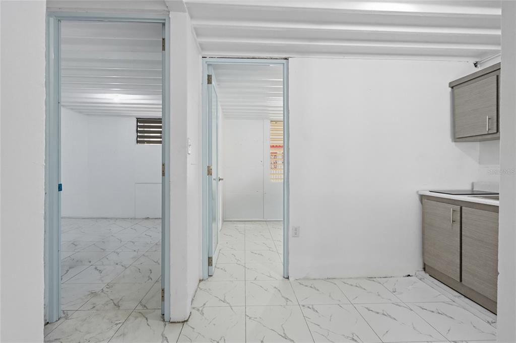 A room with white marble-patterned tile floors, two doorways, and a small kitchenette area — 36 RAMON B LOPEZ STREET, SAN JUAN, PR