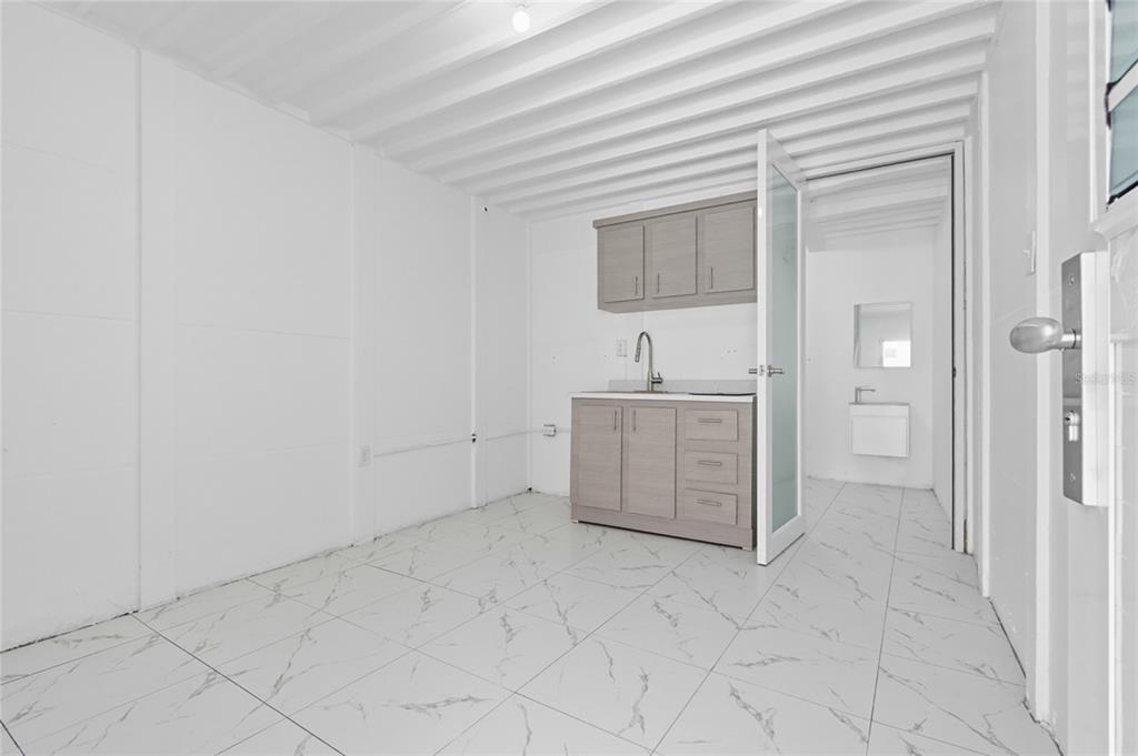 A small, white-walled room with a kitchenette, tiled floors, and a door to a bathroom — 36 RAMON B LOPEZ STREET, SAN JUAN, PR
