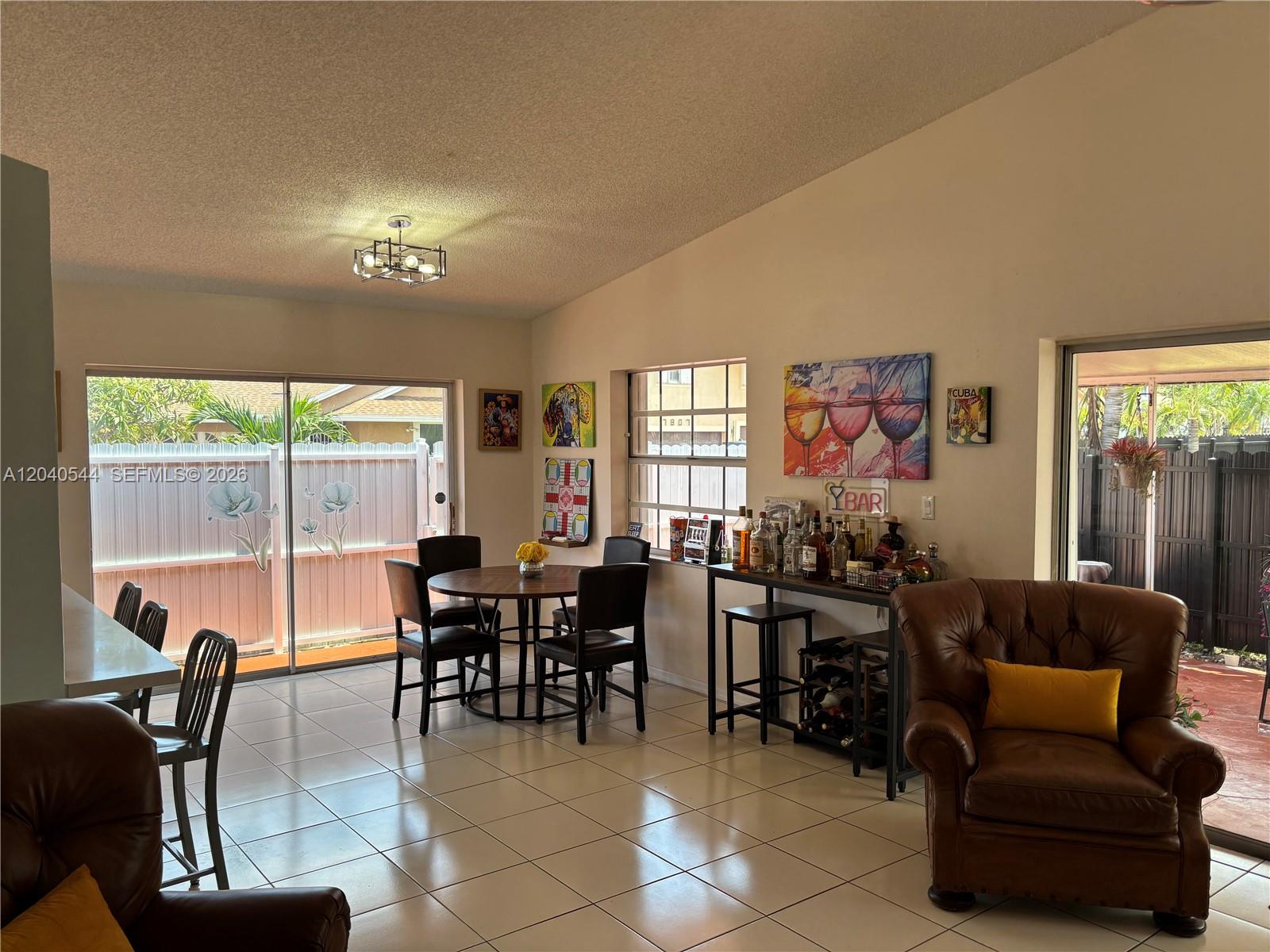 A dining area and bar space with tile floors, a leather armchair, and sliding glass doors — 18713 NW 78th Ct, Hialeah FL 33015, HIALEAH, FL