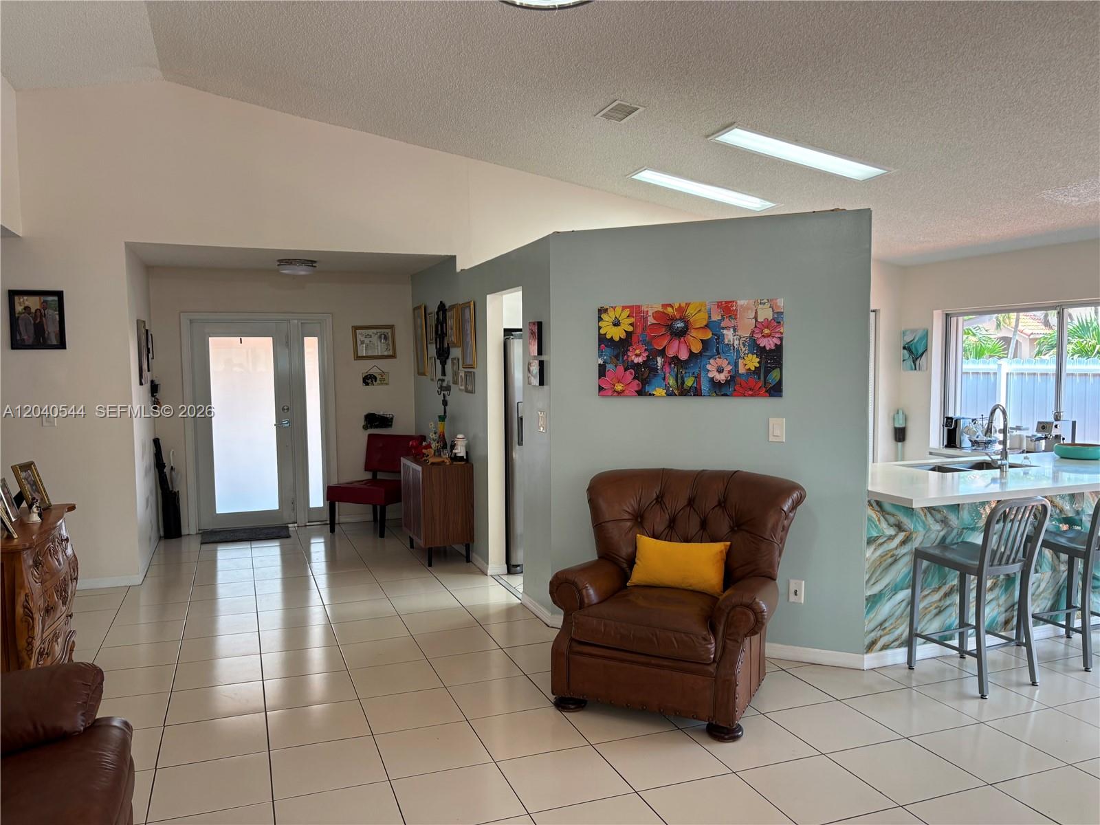 A living room features a brown leather armchair, tiled floors, and a blue accent wall — 18713 NW 78th Ct, Hialeah FL 33015, HIALEAH, FL