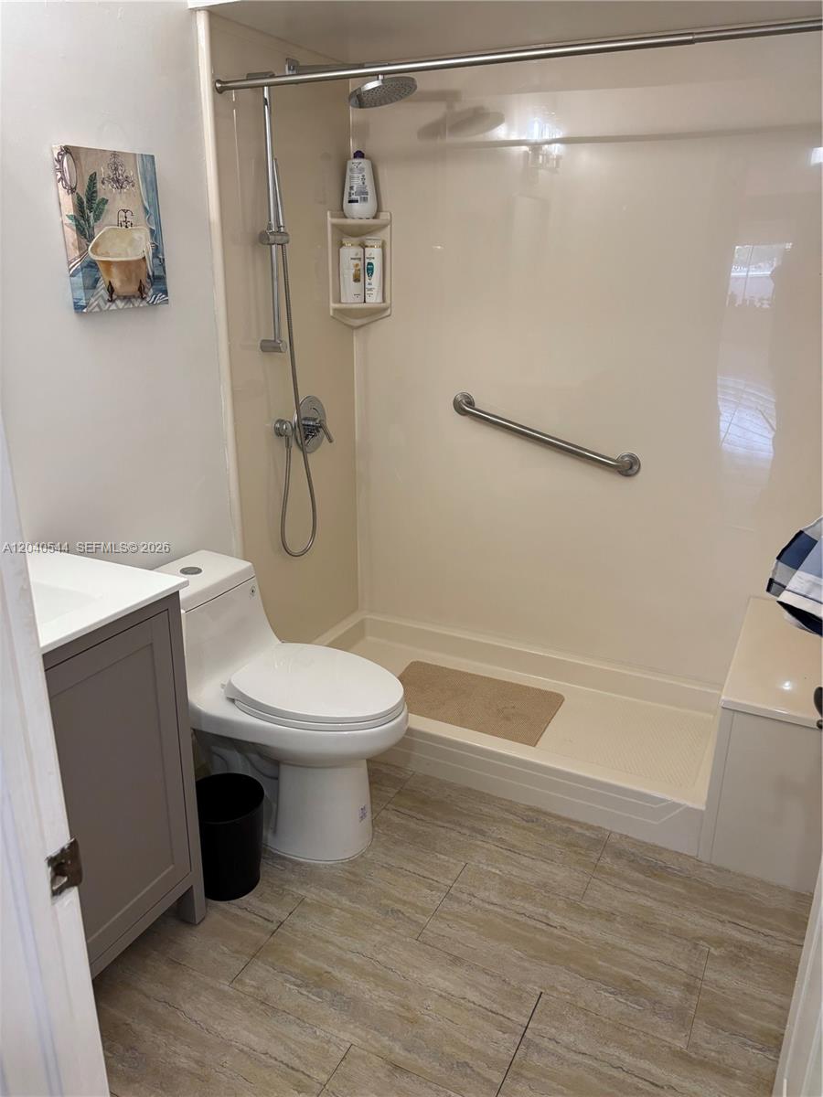 This bathroom features a walk-in shower with a grab bar, a toilet, and a vanity — 18713 NW 78th Ct, Hialeah FL 33015, HIALEAH, FL