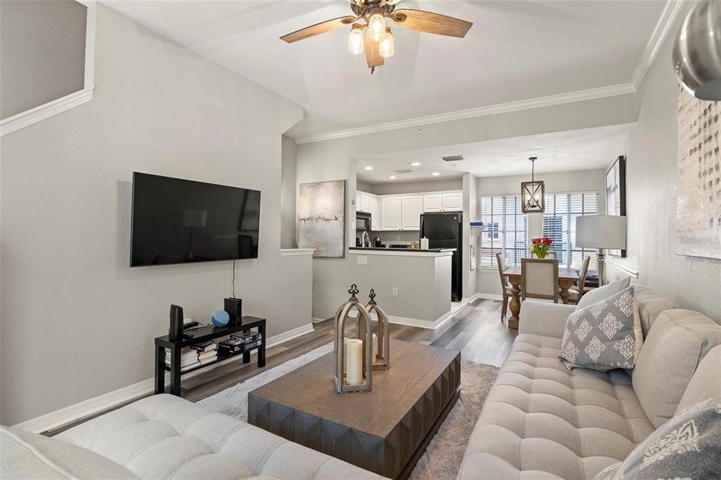 A living room with a tufted sofa, coffee table, and television opens to a kitchen — 126 BEACH HAVEN LANE UNIT 126, TAMPA, FL