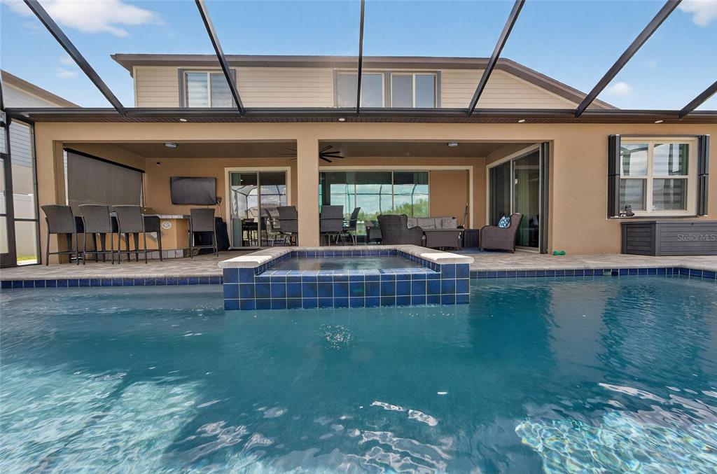 A swimming pool with a raised spa sits before a covered patio with outdoor seating — 13816 GALWAY SAND ROAD, RIVERVIEW, FL