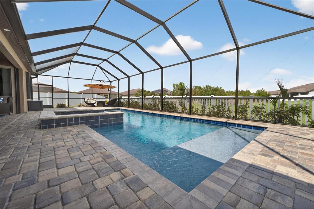 A swimming pool and hot tub are enclosed within a screened lanai with paver decking — 13816 GALWAY SAND ROAD, RIVERVIEW, FL