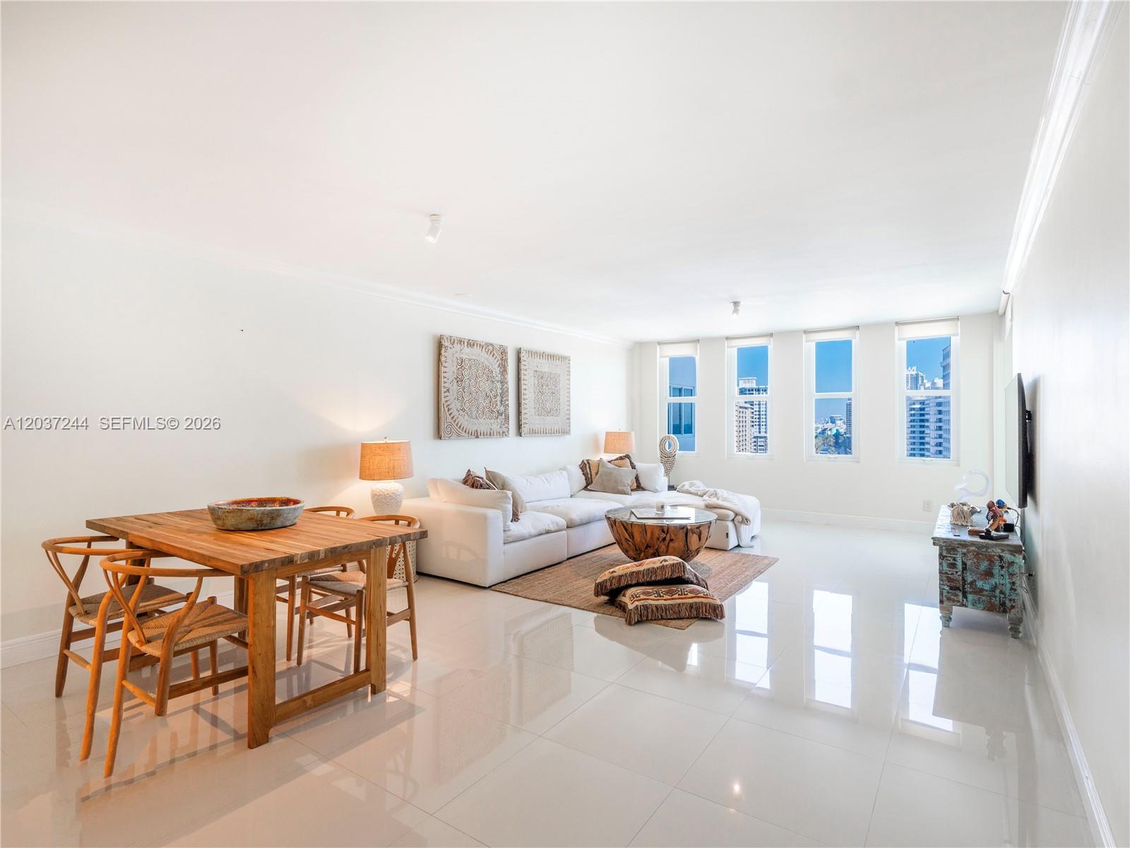 A bright living and dining area features white tile floors, a sectional sofa, and windows — 5401 Collins Ave # 1013, Miami Beach FL 33140, MIAMI BEACH, FL