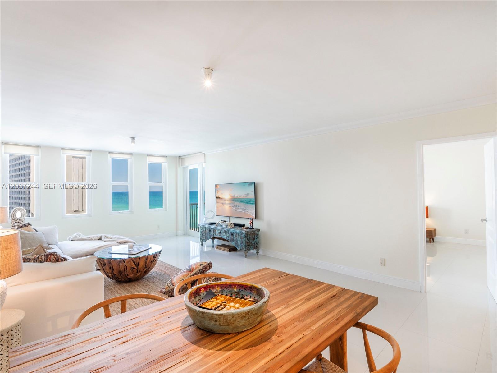 A bright living and dining area features white walls, tile floors, and ocean views — 5401 Collins Ave # 1013, Miami Beach FL 33140, MIAMI BEACH, FL