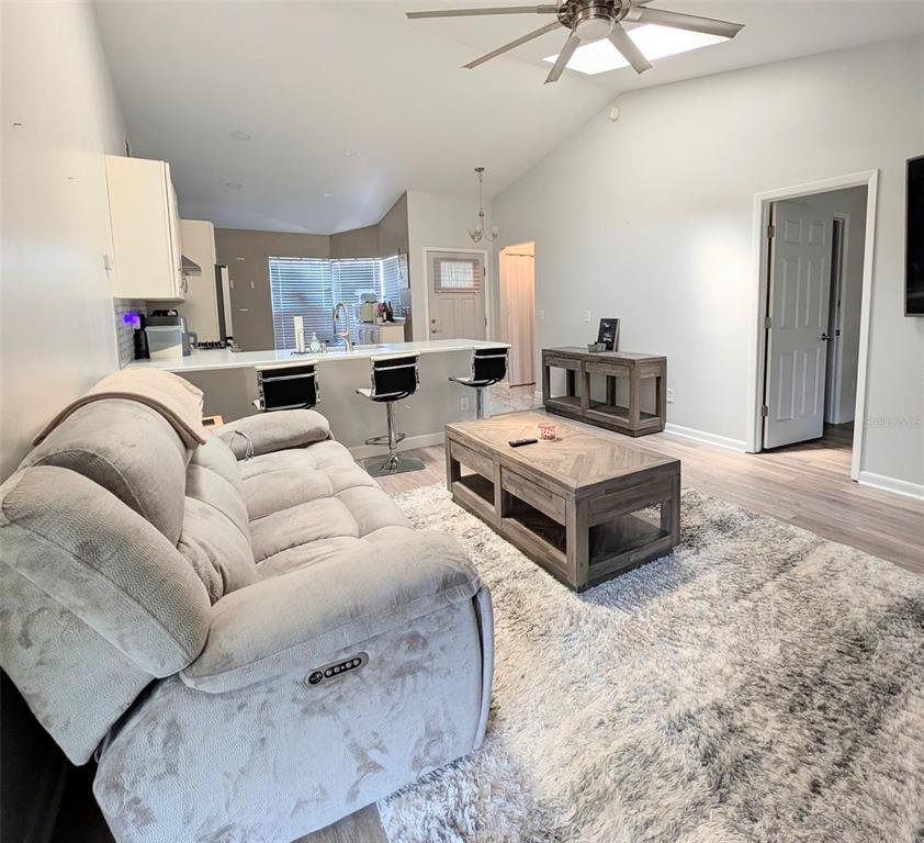 A living room with a grey sofa, wooden coffee table, and an open kitchen area — 3140 WAINWRIGHT STREET, DELTONA, FL