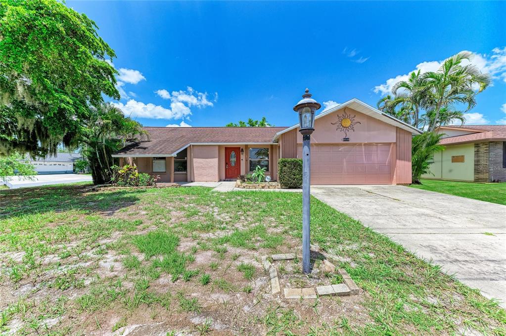 A single-story house with a pink exterior, a red front door, and a concrete driveway — 6540 MAUNA LOA BOULEVARD, SARASOTA, FL