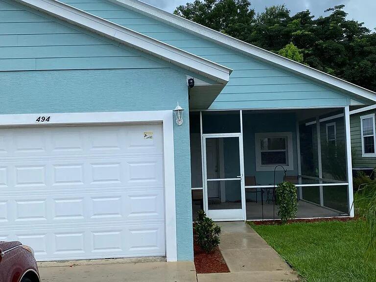 The exterior of a light blue house features a white garage door and a screened porch — 494 Oak Canopy Circle # 494, FL 33825, FL