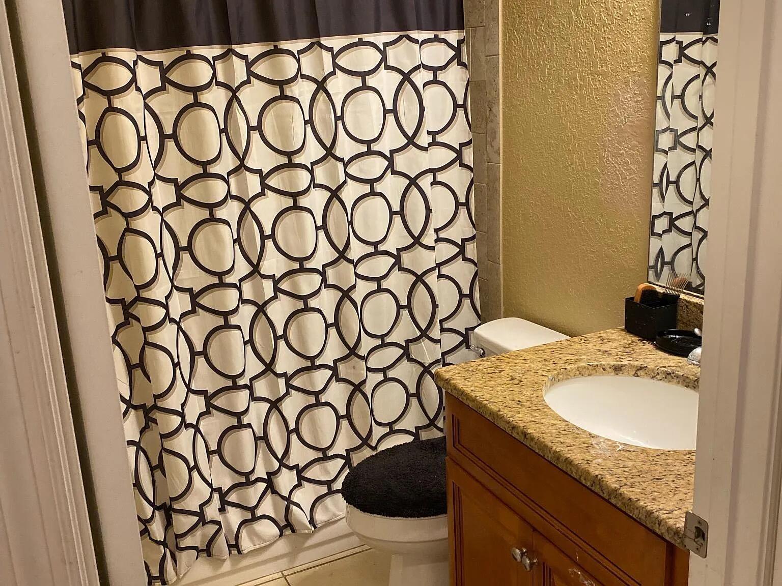 A bathroom features a patterned shower curtain, a granite vanity countertop, and a wooden cabinet — 494 Oak Canopy Circle # 494, FL 33825, FL