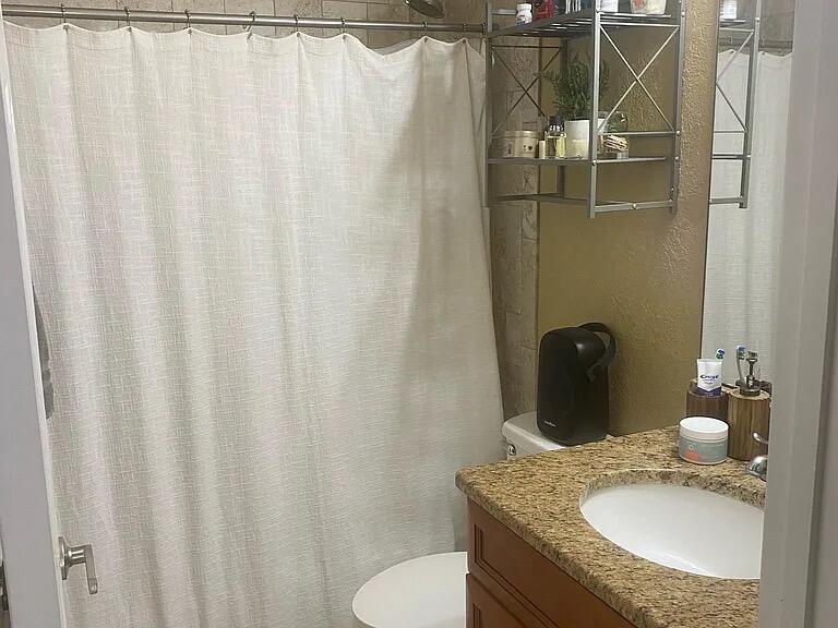 A bathroom features a granite vanity, a shower with a beige curtain, and wall-mounted shelving — 494 Oak Canopy Circle # 494, FL 33825, FL