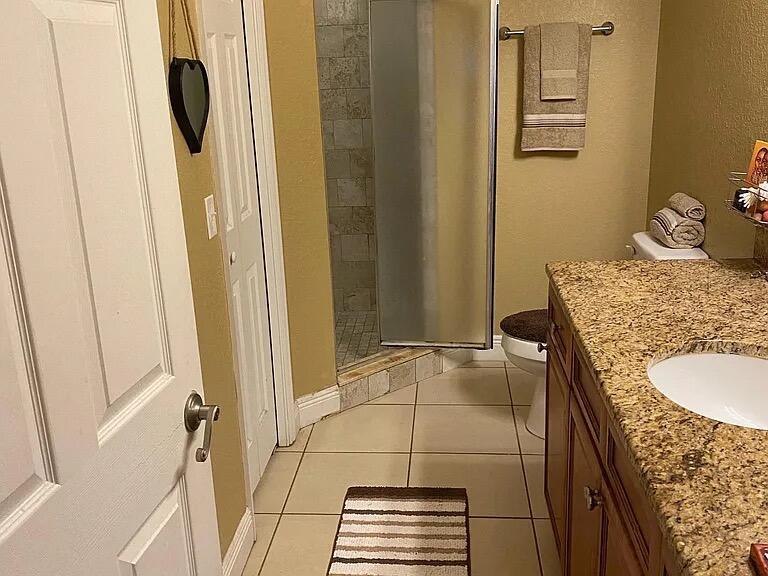 A bathroom features a granite vanity, a tiled shower, and a toilet on beige tile flooring — 494 Oak Canopy Circle # 494, FL 33825, FL