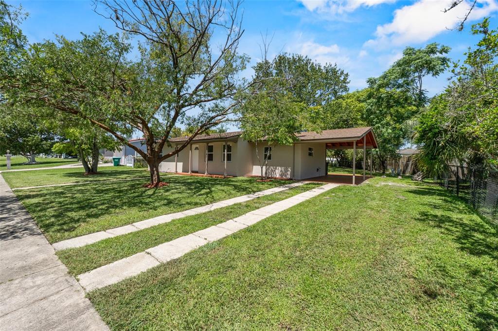 A single-story house with a carport and a concrete driveway sits on a grassy lot — 1524 PROVIDENCE BOULEVARD, DELTONA, FL