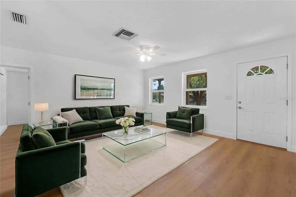 A living room features green velvet furniture, a glass coffee table, and light wood flooring — 1524 PROVIDENCE BOULEVARD, DELTONA, FL