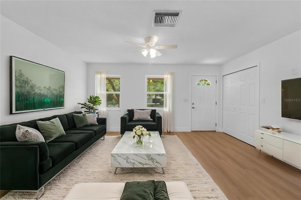 A living room features a dark green sofa, marble coffee table, and light wood flooring — 1524 PROVIDENCE BOULEVARD, DELTONA, FL