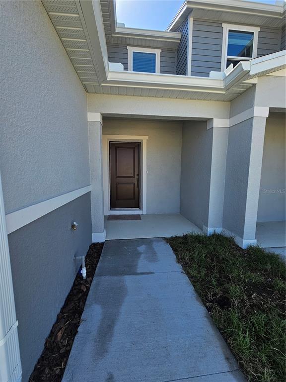 A concrete walkway leads to the covered front entryway of a gray two-story house — 9377 WESTSIDE HILLS DRIVE, DAVENPORT, FL