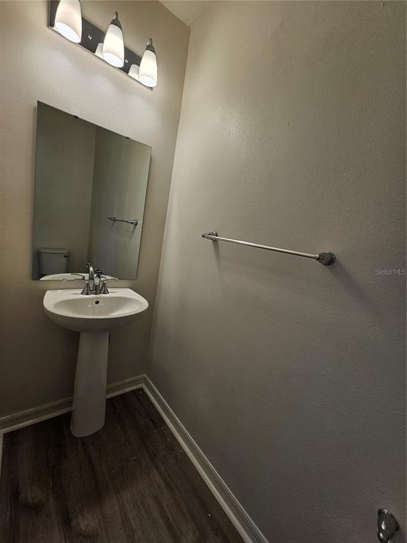 A small bathroom features a pedestal sink, a wall-mounted mirror, and a towel bar — 9377 WESTSIDE HILLS DRIVE, DAVENPORT, FL
