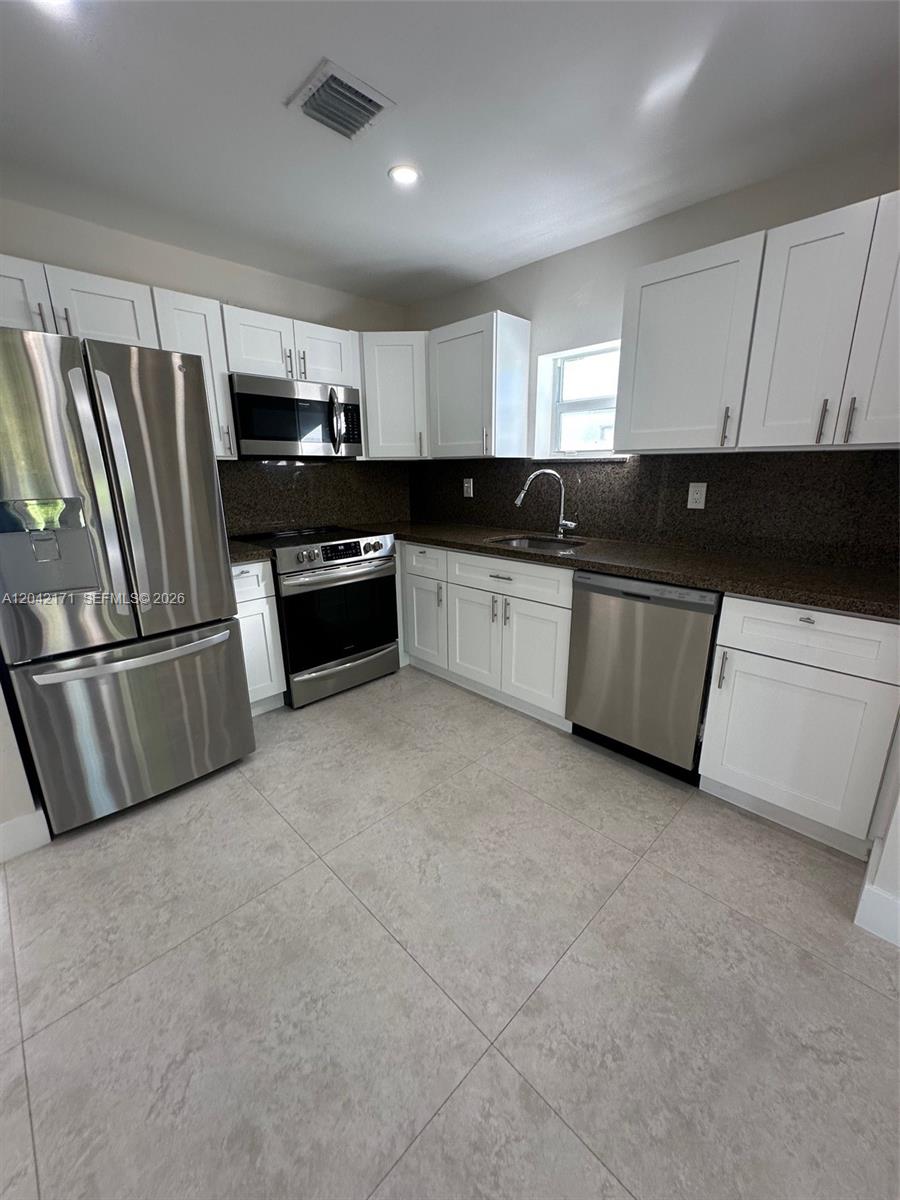A kitchen features white cabinets, stainless steel appliances, and dark granite countertops — MIAMI, FL