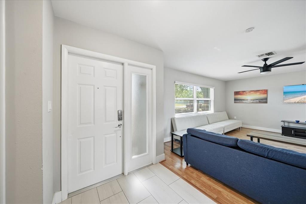 An entryway with white tile flooring leads into a living room with hardwood floors — 5883 WHISTLEWOOD CIRCLE, SARASOTA, FL