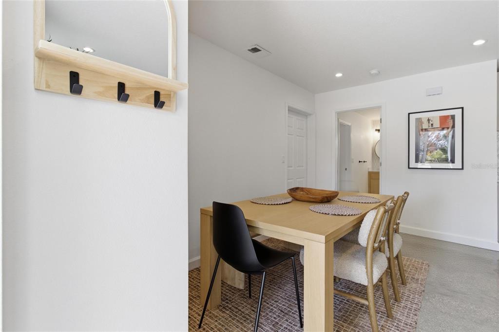 A dining area features a light wood table, a black chair, and textured chairs — 2121 PALM TERRACE, SARASOTA, FL