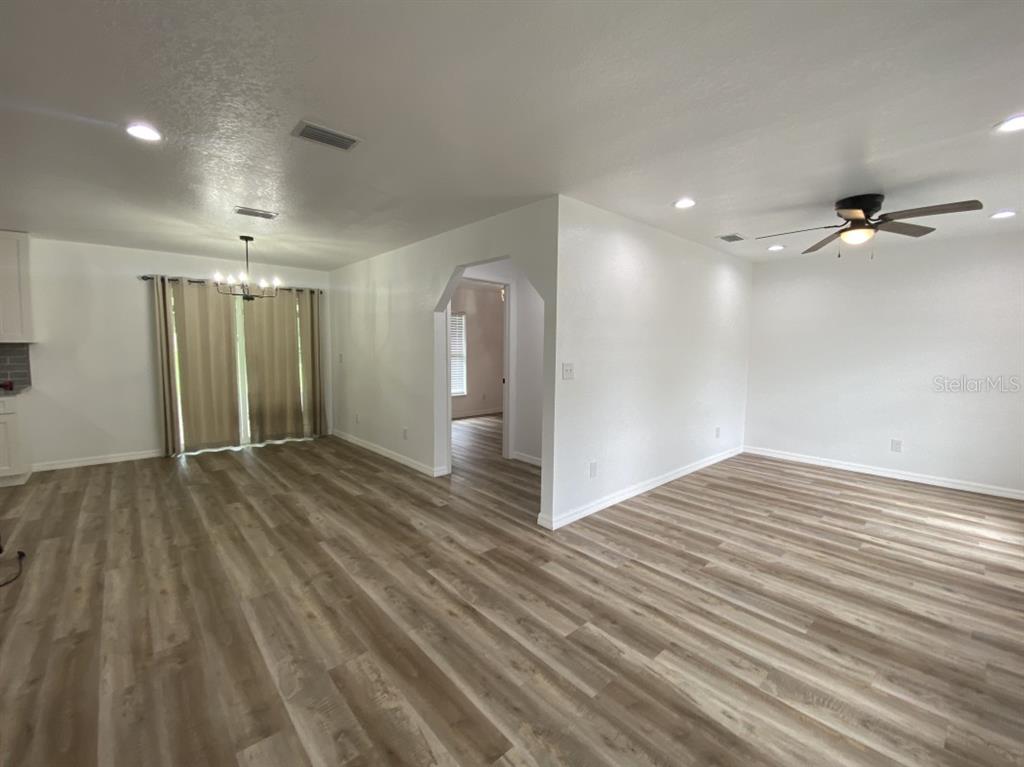 An open-concept living and dining area features light wood-look flooring and white walls — 4333 NE 22ND COURT, OCALA, FL