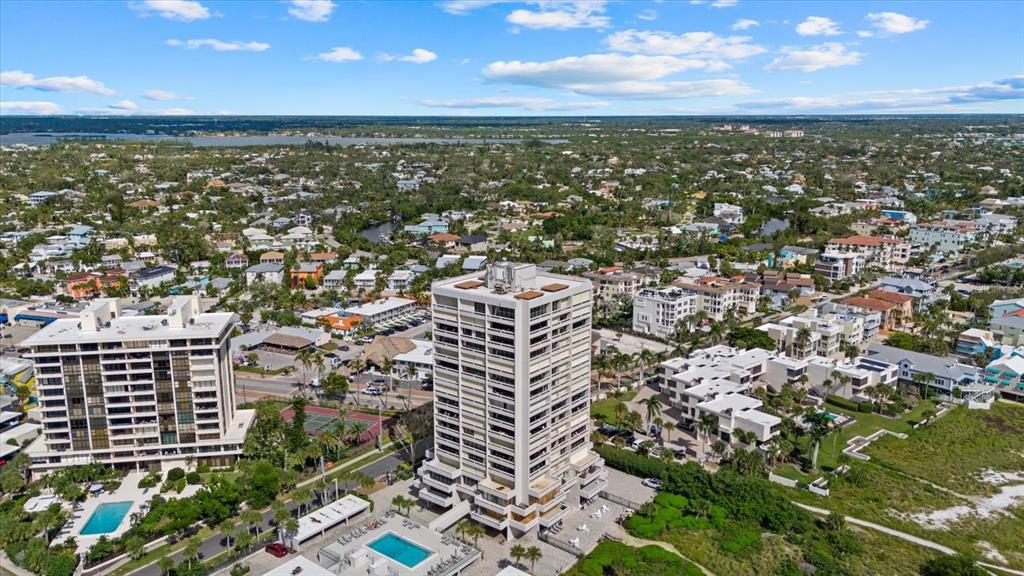 An aerial view shows a tall residential building near a beach, pool, and tennis court — 5400 OCEAN BOULEVARD UNIT 17-04, SARASOTA, FL