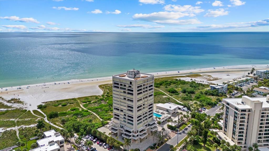 An aerial view shows a tall residential building situated next to a sandy beach — 5400 OCEAN BOULEVARD UNIT 17-04, SARASOTA, FL