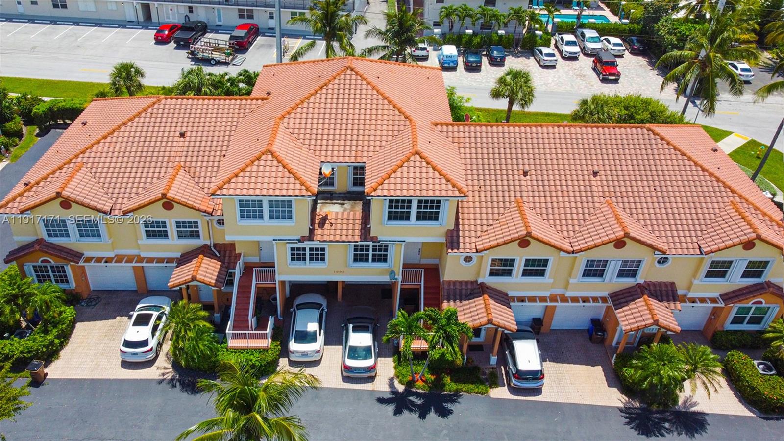 An aerial view shows a multi-unit residential building with a tiled roof and parking spaces — 1998 NE 7th St # 104, Deerfield Beach FL 33441, DEERFIELD BEACH, FL
